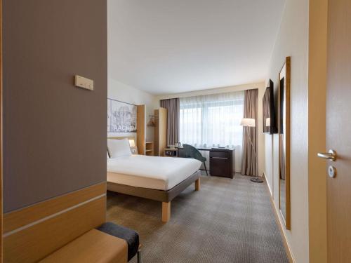 a hotel room with a bed and a window at Novotel Aachen City in Aachen