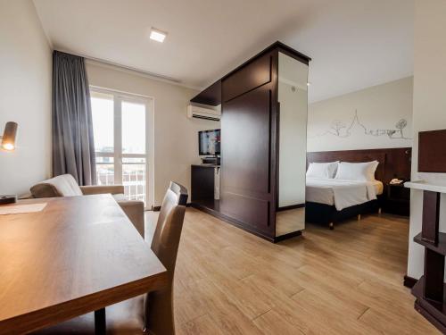 a hotel room with a bed and a table at Mercure Jaragua do Sul in Jaraguá do Sul