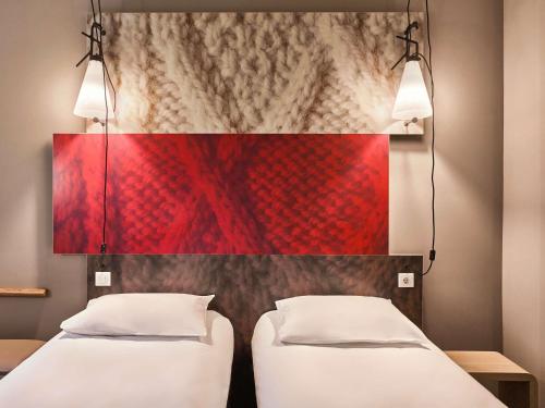 two beds in a room with a red wall at ibis Hotel Hamburg St. Pauli Messe in Hamburg