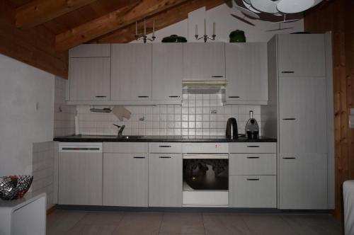 a kitchen with white cabinets and an oven at Casa Sagogn Laax in Sagogn