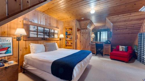 a bedroom with a bed and a red chair at Homewood Lakefront by AvantStay Private Beach Lake Access Views in Homewood