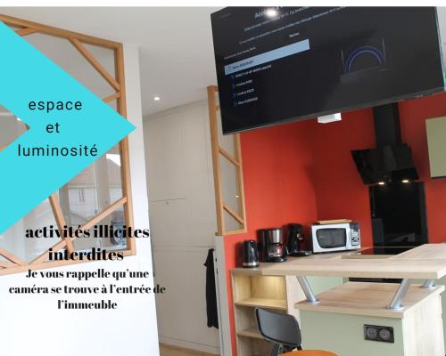 a tv in a room with a table with a microwave at Appartement Cosy avec Sauna - Angouleme - 4 personnes in Angoulême