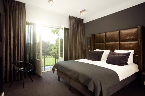 a bedroom with a large bed and a balcony at Hotel Restaurant De Wolfsberg in Groesbeek