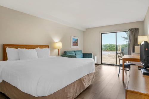 Cette chambre comprend un grand lit et une porte coulissante en verre. dans l'établissement Rodeway Inn, à Saint-Jean