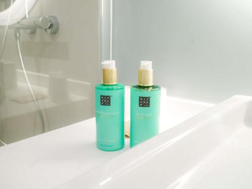two green bottles ofodorizers sitting on a bathroom sink at Novotel Monte-Carlo in Monte Carlo
