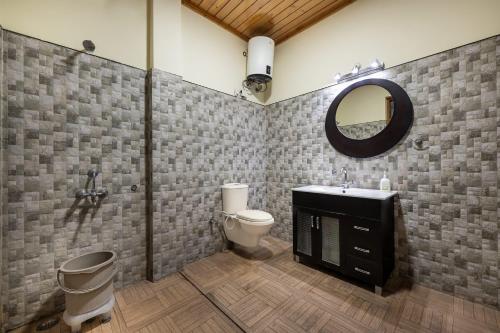 Un baño con inodoro, lavabo y espejo. en Suffer Heights Kasauli I Vacations I Family Groups & Events I Forest Treks I Memories Toy Train View I Serviced Apartments I Kasauli By Exotic Stays, en Kasauli