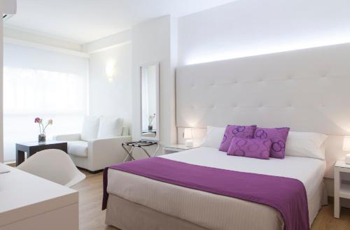 a white bedroom with a large bed with purple pillows at Hotel Albahia Alicante in Alicante