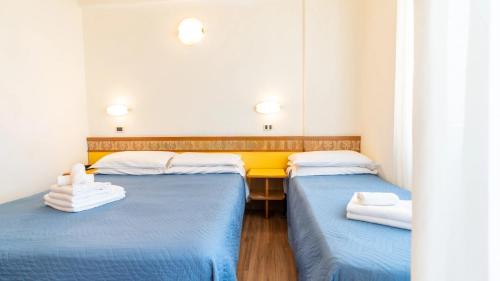 2 camas en una habitación de color azul y amarillo en Hotel Cosmopol Cesenatico, en Cesenatico
