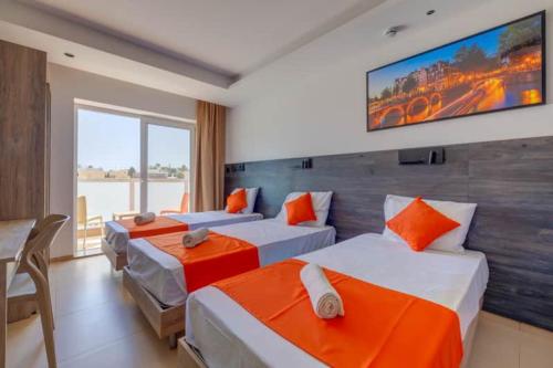 a bedroom with two beds and a tv on the wall at Bayside A Apartments in St Julian's