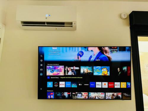 a flat screen tv hanging on a wall at Wake up in white - Private Jacuzzi & cotton comfort in Verdun