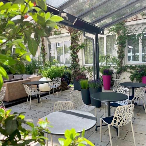 a patio with tables and chairs and plants at Boutique Hotel Atrium München in Munich