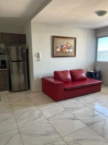 a living room with a red couch and a refrigerator at Brisa Marina Departamento con Alberca y Playa in Boca del Río