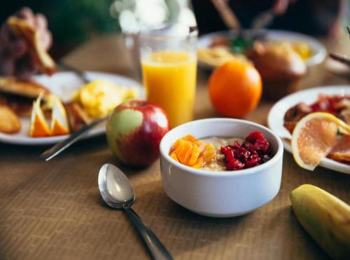 a table with a bowl of cereal and fruit and a glass of orange juice at Hotel The Grand Olive Aero Suites Near Delhi Airport in New Delhi