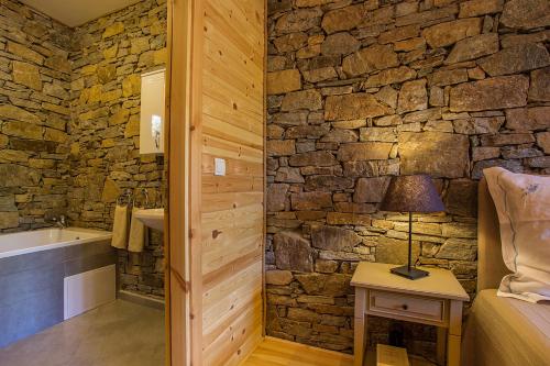 Un baño con paredes de piedra con una cama y una bañera. en Garmen Hills Guest Houses, en Garmen