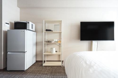 a hotel room with a refrigerator and a tv at Eruza HAKATA エルザ博多 in Fukuoka