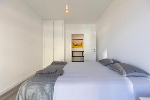 a white bedroom with a large bed with blue pillows at Comfort & Style w/ best sea view in Sesimbra