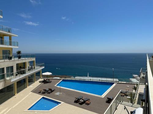 a swimming pool on top of a building with the ocean at Comfort & Style w/ best sea view in Sesimbra