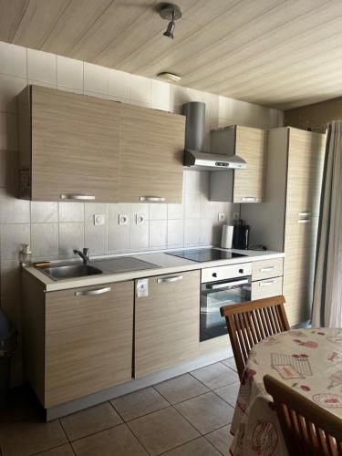 a kitchen with wooden cabinets and a sink and a table at Domaine de La Nouillière - Jacuzzi in Saint-Nicolas-de-Bourgueil