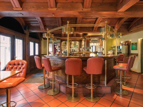 a bar in a restaurant with red chairs at Mercure Hotel Düsseldorf City Center in Düsseldorf