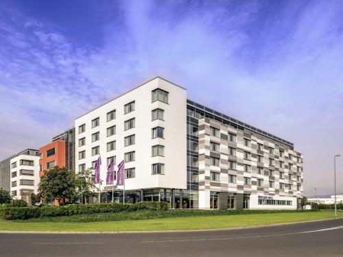 a large white building on the side of a street at Mercure Hotel Frankfurt Eschborn Helfmann-Park in Eschborn