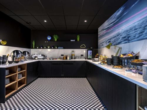 una cocina con armarios negros y suelo ajedrezado en Mercure Neu-Isenburg, en Neu Isenburg