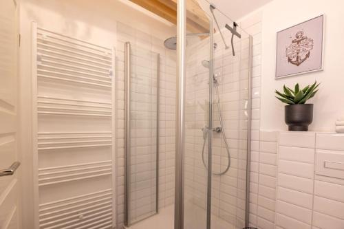 a shower in a bathroom with white tiles at Nordseenest in Krummhörn