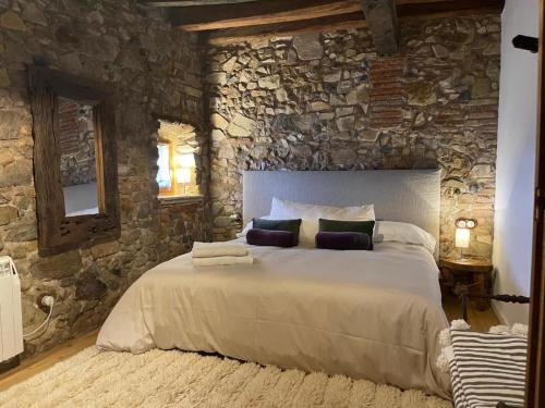 a bedroom with a large bed in a stone wall at Más Figueres in Caldes de Malavella