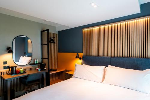 a bedroom with a bed and a desk and a mirror at Village Hotel Reading in Caversham