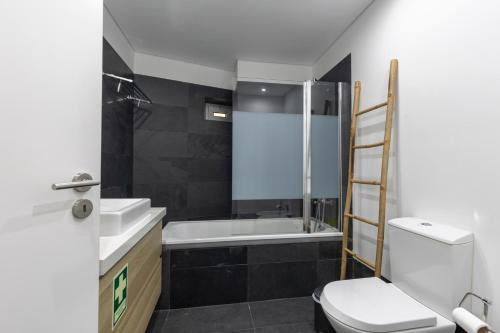 a bathroom with a toilet and a sink and a tub at Iva's Panoramic Sesimbra in Sesimbra
