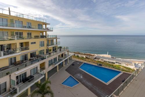 an apartment building with a swimming pool and the ocean at Iva's Panoramic Sesimbra in Sesimbra