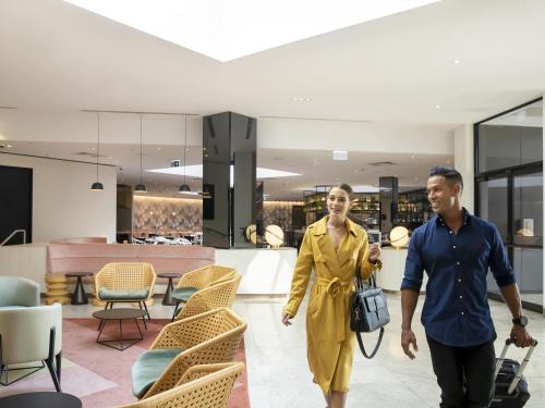 Un uomo e una donna che camminano in un negozio di Novotel Sydney International Airport a Sydney