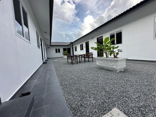 une cour d'un bâtiment blanc avec une plante en pot dans l'établissement cheta roomstay, à Gua Sai