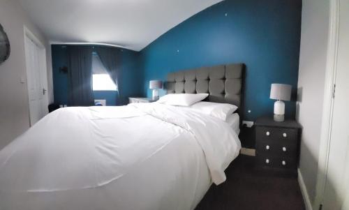 a bedroom with a white bed with a blue wall at Morayo in Sandal and Walton