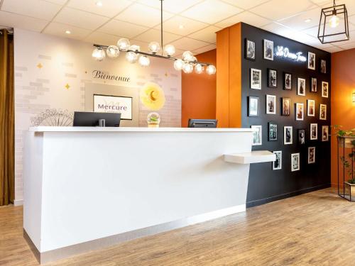 an office with a reception counter and pictures on the wall at Mercure Lyon Est Chaponnay in Chaponnay