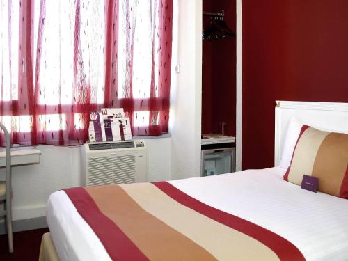 a bedroom with a bed and a window with red curtains at Mercure Limoges Centre in Limoges