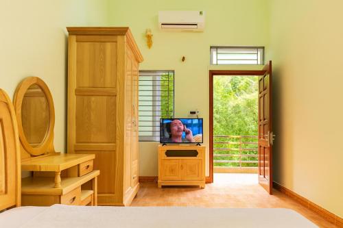 a bedroom with a tv on a dresser with a window at Phuong Linh Hotel in Bảo Lạc
