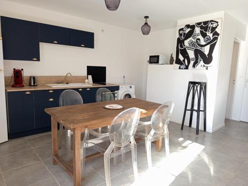 Una cocina con una mesa y sillas de madera. en L'annexe Barberousse, en Toulenne