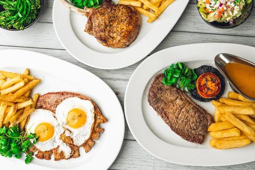 three plates of food with eggs and french fries at Village Hotel Reading in Reading