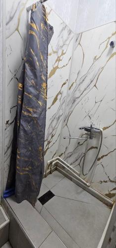 a shower in a bathroom with a marble wall at Shinam Hostel in Chilanzar