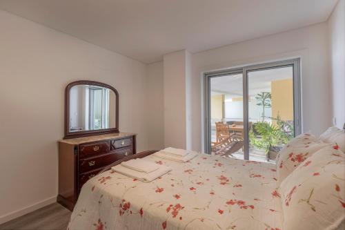 a bedroom with a bed with a dresser and a mirror at Sea Sound Apartment by Trip2Portugal in Sesimbra