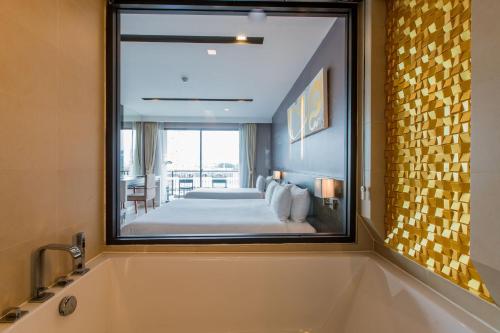 a bathroom with a large mirror over a tub at The Charm Resort Phuket in Patong Beach