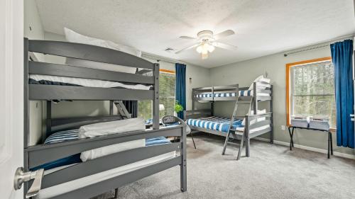 1 dormitorio con 3 literas y ventilador de techo en Rustic-Chic Escape w Hot Tub Fireplace Nature Views Pine Woods Loft, en Lehigh