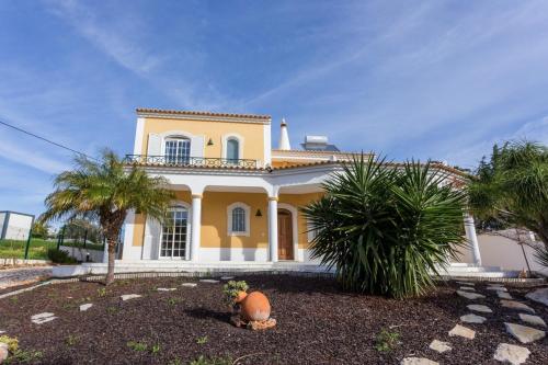 a yellow house with palm trees in front of it at Villa Coelho by Trip2Portugal in Olhão
