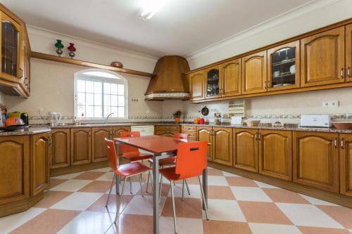 a kitchen with wooden cabinets and a table and chairs at Villa Coelho by Trip2Portugal in Olhão