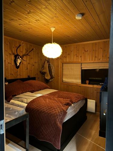 a bedroom with a bed and a chandelier at Spacious modern family chalet in Solhovda close to hiking, skiing & nature in Hol