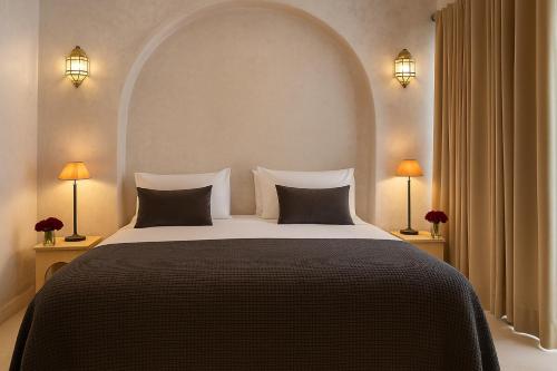 Un dormitorio con una cama grande con dos lámparas. en Riad Dar More, en Marrakech