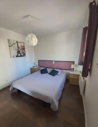 a bedroom with a white bed with two pillows at Apartment L'Aquarius in Villeneuve-le-Roi