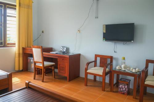a room with a desk and chairs and a tv at Hồng Ân Motel Quảng Trị in Quảng Trị