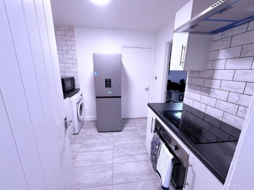 a kitchen with a refrigerator and a washer and dryer at Beautiful, modern and spacious one-bedroom apartment, fully equipped with free parking in Erith
