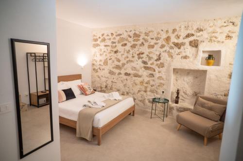 a bedroom with a bed and a chair and a stone wall at Dimora Lincoln in Grotte